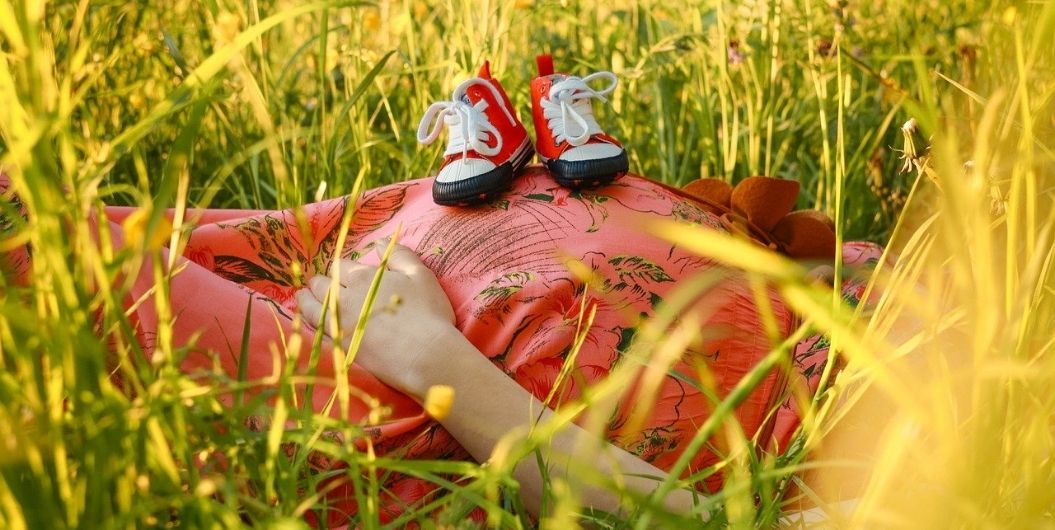 pregnant woman laying on grass