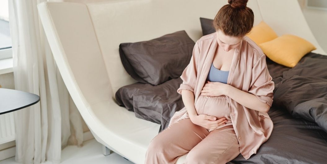 pregnant woman sitting on a bed