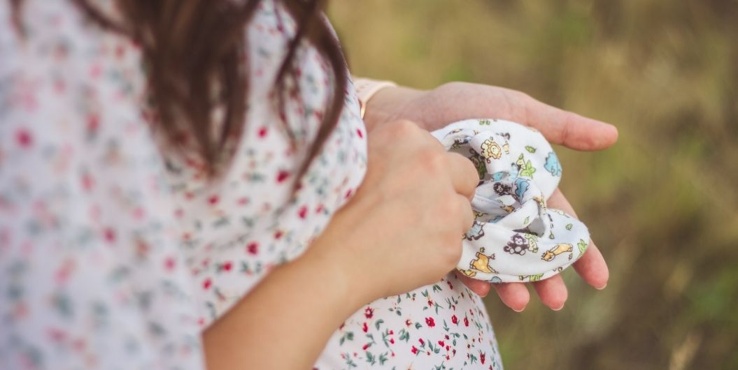 pregnant woman holding baby's shoes