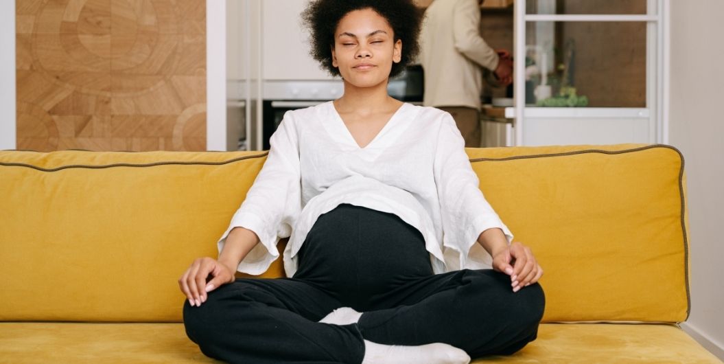 pregnant woman meditating on couch