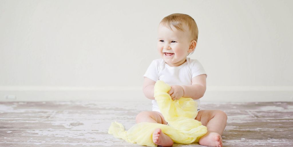 happy baby playing a yellow cloth